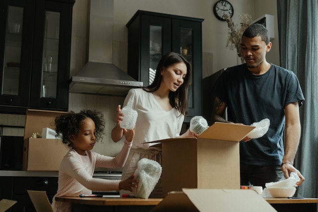 Family of three packing moving boxes together